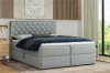 Grijs boxspringbed met elegante knoopstiksels op het hoofdbord en blauwe deken.