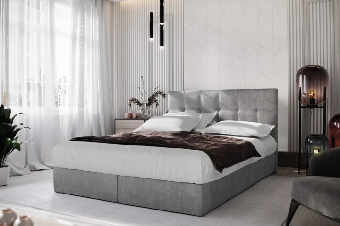 Modern ingerichte slaapkamer met grijs boxspringbed en elegante decoratie.