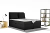Zwart boxspringbed van corduroy in een slaapkamerambiance met rek en lamp.