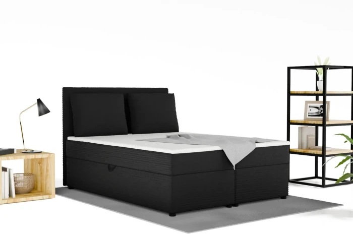 Zwart boxspringbed van corduroy in een slaapkamerambiance met rek en lamp.