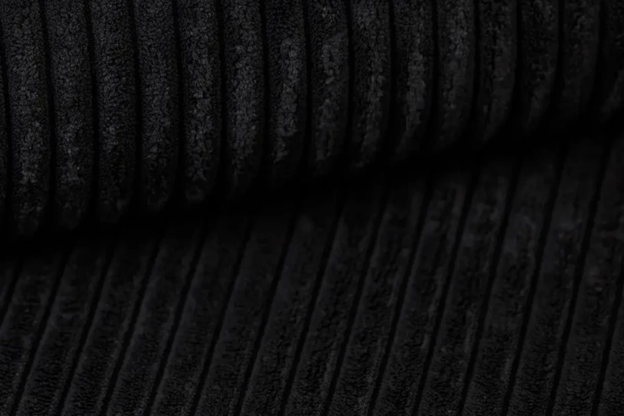 Textuur-detailopname van de zwarte corduroy stof van een boxspringbed.