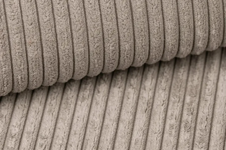 Close-up van de zachte corduroy-structuur van het boxspringbed Tami in de kleur beige.