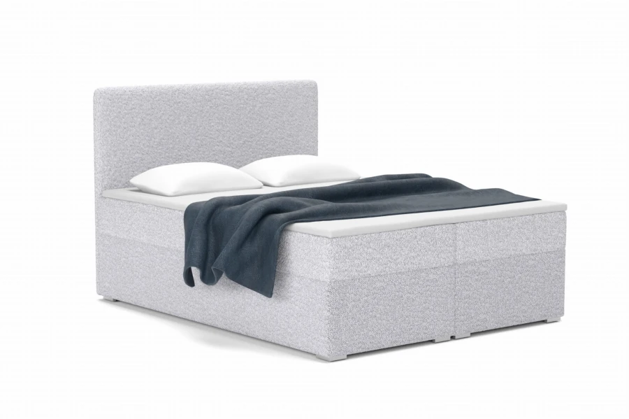 Silbergraues Boxspringbett mit Bouclé-Bezug und dunkelblauer Decke.