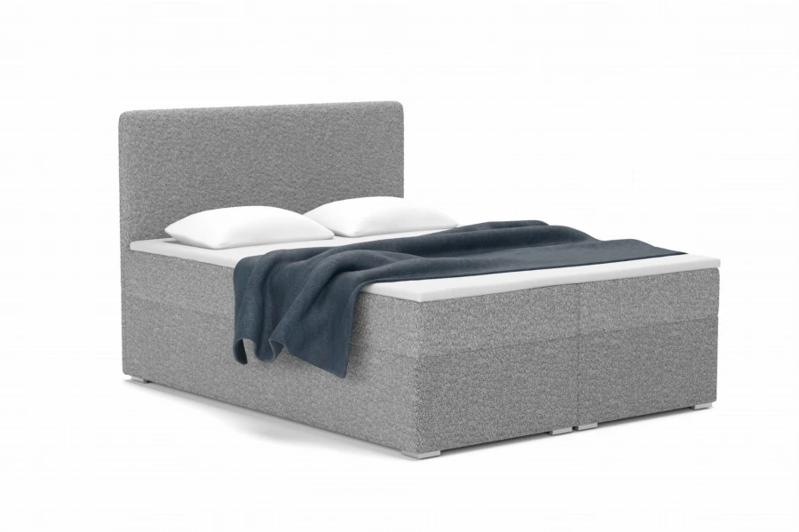 Graues Boxspringbett mit weichem Bouclé-Bezug und blauer Decke.
