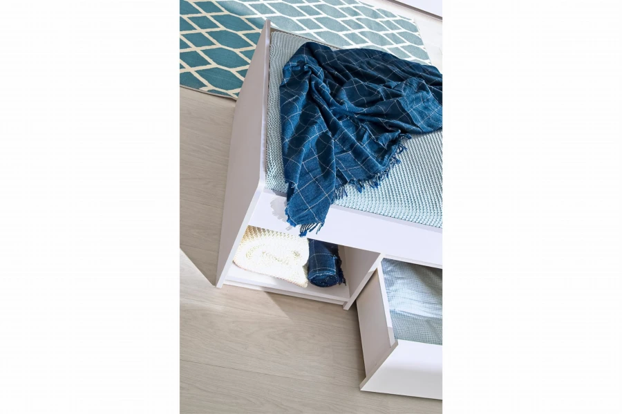 Weißes Jugendbett mit praktischen Schubladen und blauer Decke.
