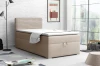 Beige boxspringbed met gestoffeerd hoofdbord in een moderne kamer met witte bakstenen muur.