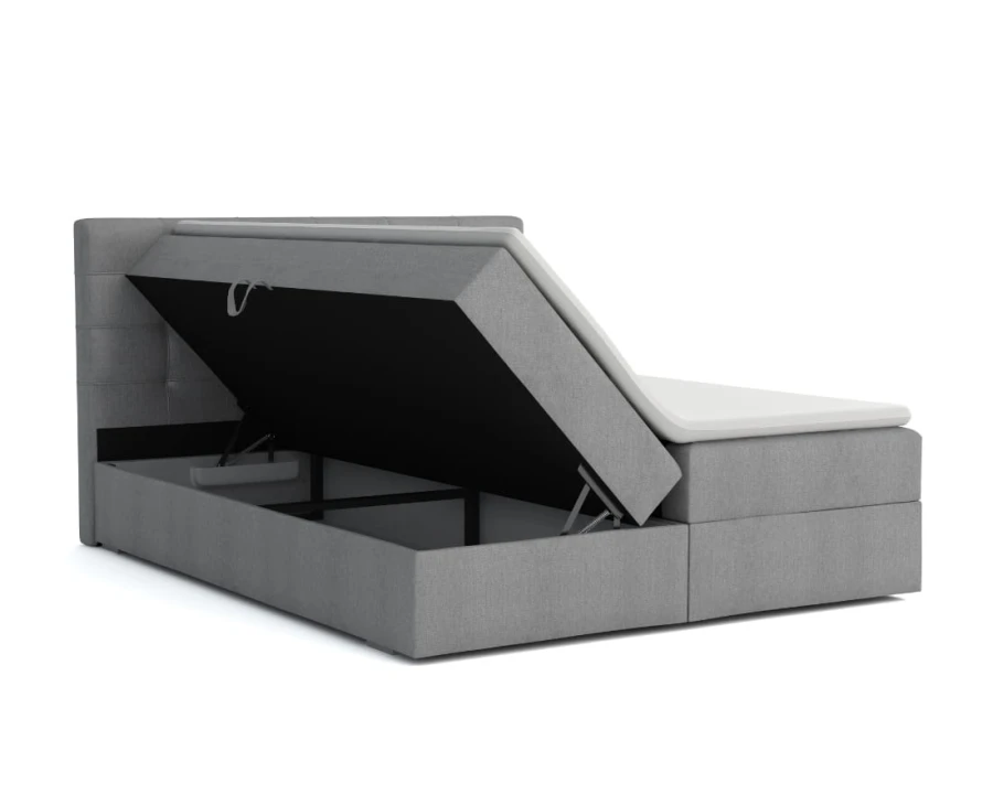 Graues Boxspringbett mit geöffnetem Bettkasten für viel Stauraum unter der Matratze.