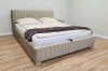 Modernes beige Polsterbett mit vertikal gestepptem Kopfteil in einem hellen Schlafzimmer.