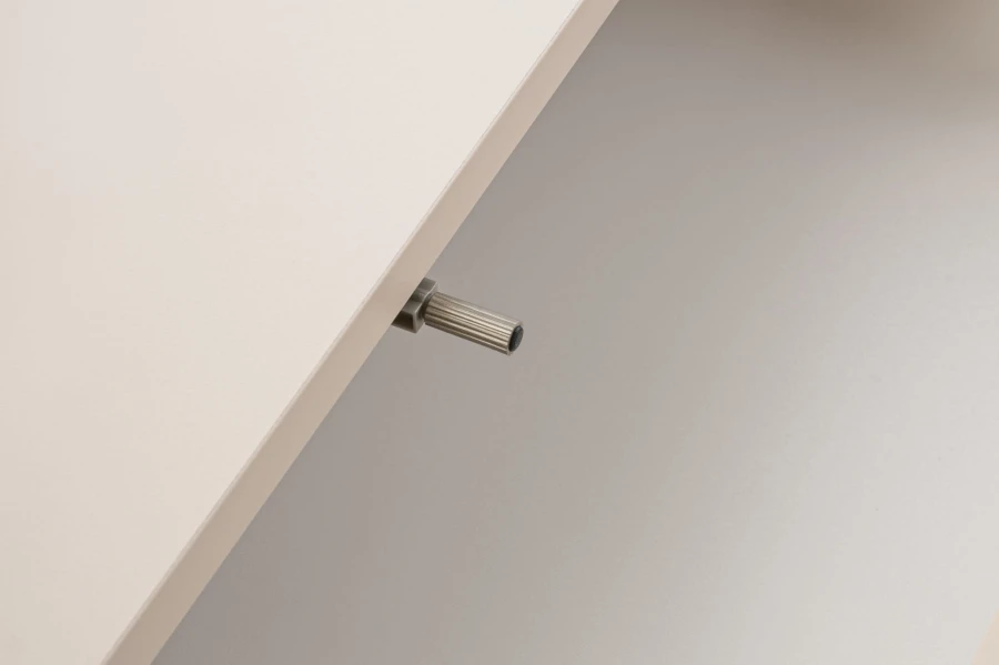Detailansicht eines Push-to-open-Mechanismus an einem hellen Möbelstück.