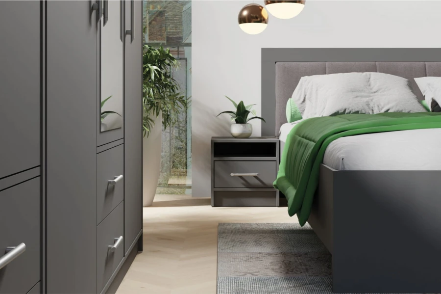Moderner Nachttisch in Anthrazit neben einem Bett mit grüner Decke.