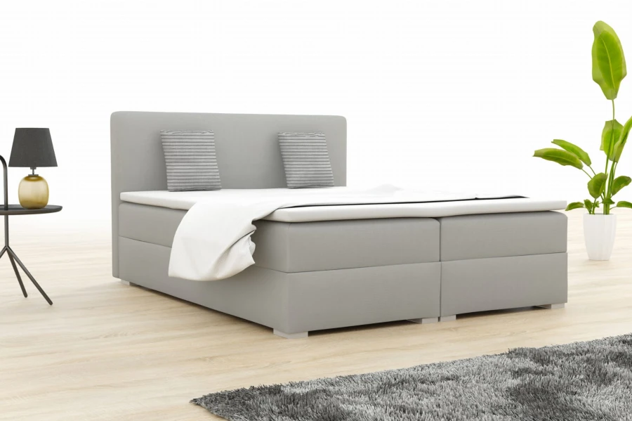Hellgraues Boxspringbett im modernen Schlafzimmer mit Pflanze.