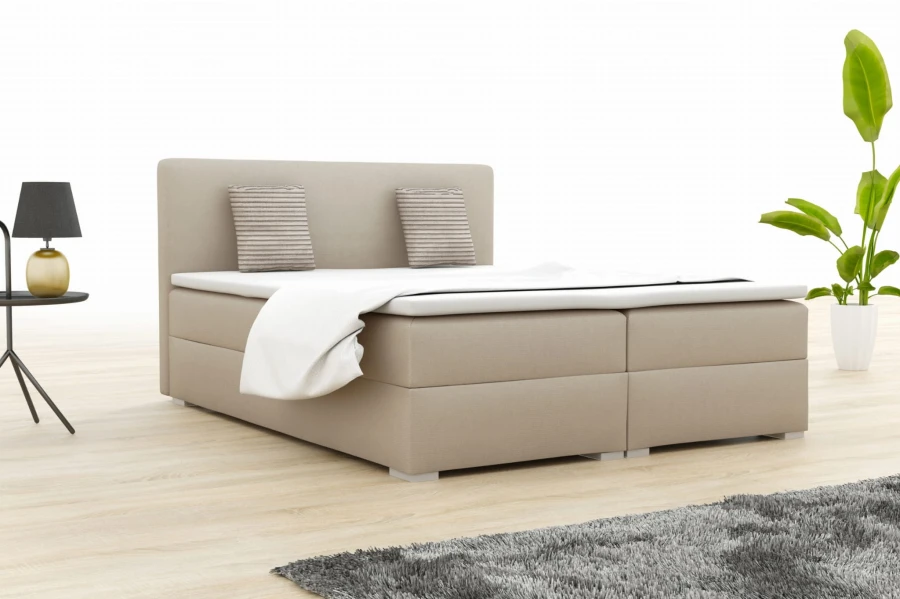 Beige boxspring bed in a bedroom with modern furnishings and a plant.