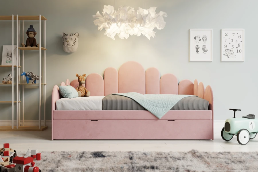 Rosa Kinderbett mit gewelltem Kopfteil und praktischer Ausziehschublade in einem hellen Kinderzimmer.