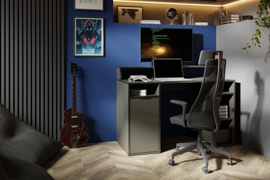 Gaming-Zimmer mit Schreibtisch Karo in Grau, Laptop, Monitor und ergonomischem Bürostuhl vor blauer Wand.