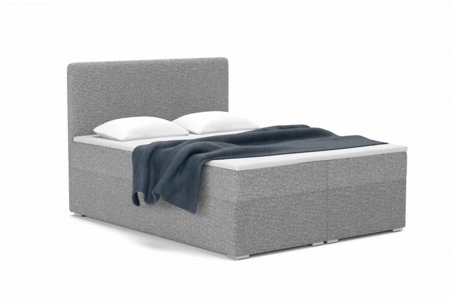 Modern bouclé boxspringbed in grijs met witte kussens en blauwe deken.