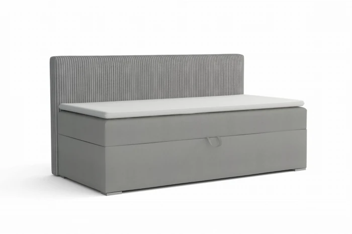Modern grijs boxspring eenpersoonsbed met geribbeld hoofdbord en witte topper.