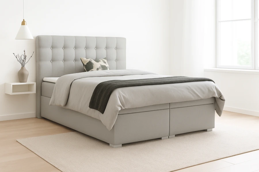 Modernes hellgraues Boxspringbett im Schlafzimmer mit gepolstertem Kopfteil und Bettwäsche.