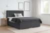 Modernes dunkelgraues Boxspringbett in einem hellen Schlafzimmer-Ambiente.