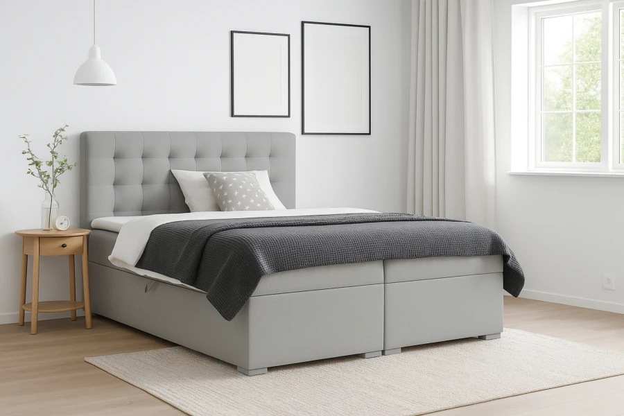 Modernes Boxspringbett in Hellgrau mit gestepptem Kopfteil in einem hellen Schlafzimmer.