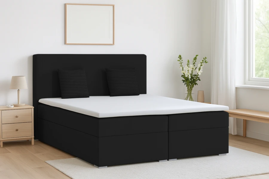 Schwarzes Boxspringbett in modernem Schlafzimmer mit weißem Topper und Dekokissen.