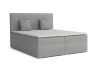 Graues Boxspringbett mit gepolstertem Kopfteil und Dekokissen vor weißem Hintergrund.