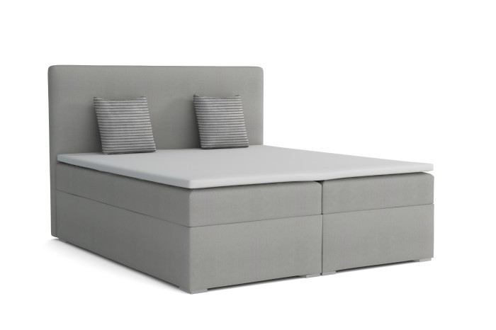 Grijs gestoffeerd boxspringbed met twee kussens en witte topper op witte achtergrond.
