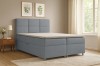 Modernes Boxspringbett in Grau in einem hellen Schlafzimmer mit Teppich und Bildern.