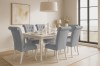 Modernes Esszimmer-Set mit weißem Tisch und sechs hellblauen Polsterstühlen im Landhausstil.