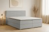 Modernes Boxspringbett mit grauem Cordbezug in einem hellen Schlafzimmer.