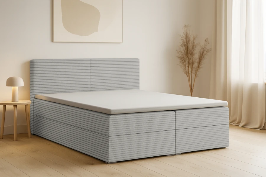 Modernes Boxspringbett mit grauem Cordbezug in einem hellen Schlafzimmer.