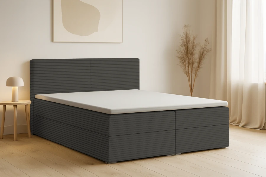 Dunkelgraues Boxspringbett mit Cord-Struktur in gemütlichem Schlafzimmer-Ambiente.