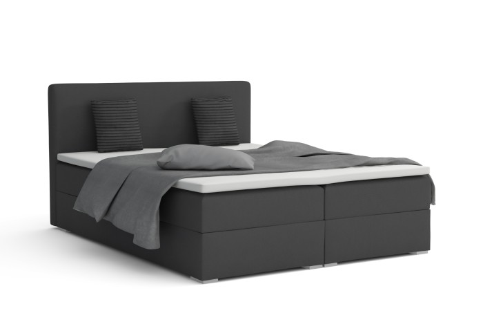 Donkergrijs boxspringbed Bello met kussens en topper tegen een witte achtergrond.