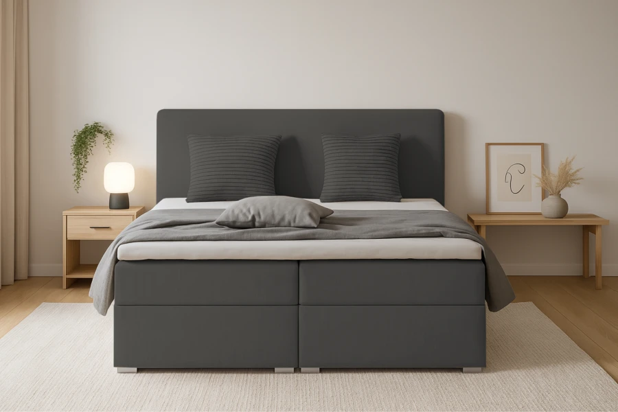 Vooraanzicht van een comfortabel boxspringbed in donkergrijs met kussens.