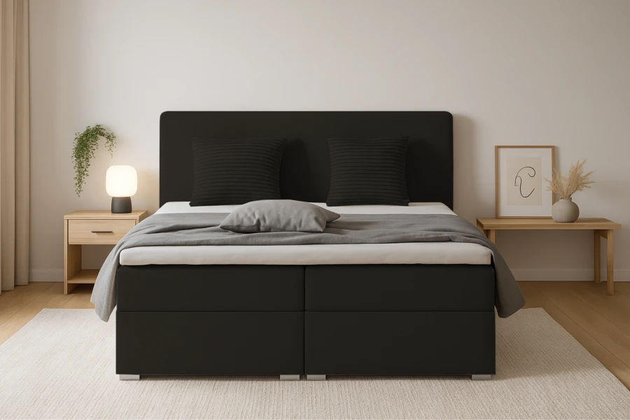 Vooraanzicht boxspringbed Bello in zwart met grijs deken en kussens.