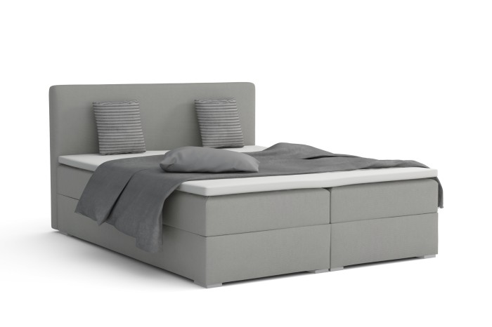 Bello Boxspringbett in Grau mit grauen Kissen und Decke, freigestellt auf Weiß.