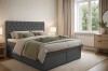 Graues Boxspringbett Arami mit dekorativem Kopfteil und Kissen in hellem Schlafzimmer.