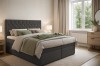 Modernes Schlafzimmer mit einem dunkelgrauen Boxspringbett, Holzkommode und Fenster.
