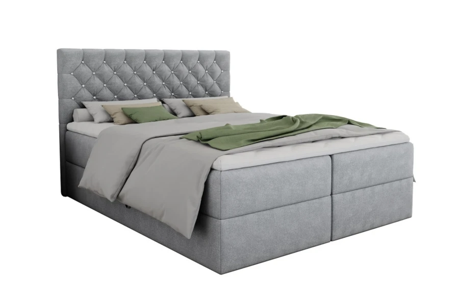 Graues Boxspringbett mit elegant gestepptem Kopfteil und grünen Kissen auf weißem Hintergrund.