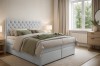 Modernes Boxspringbett in Grau in einem hellen, gemütlich eingerichteten Schlafzimmer.