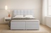 Hellblaues Boxspringbett mit quadratisch gestepptem Kopfteil in minimalistischem Design.