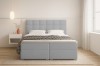 Blaues Boxspringbett mit hohem Kopfteil und geometrisch gemusterter Bettdecke.