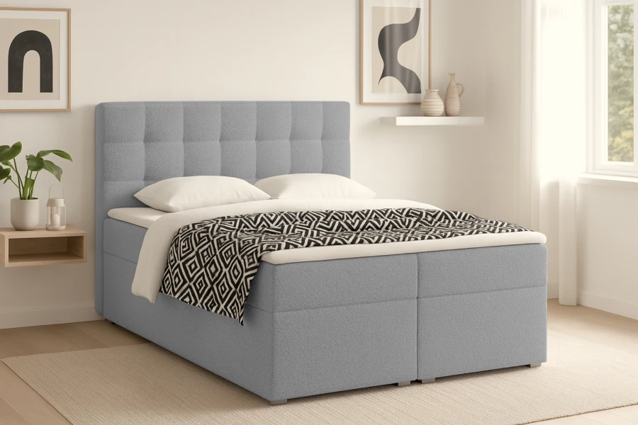 Hellblaues Boxspringbett mit gestepptem Kopfteil und schwarz-weißer Tagesdecke im Schlafzimmer.