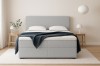 Hellgraues Boxspringbett in Frontalansicht mit minimalistischer Schlafzimmer-Deko.