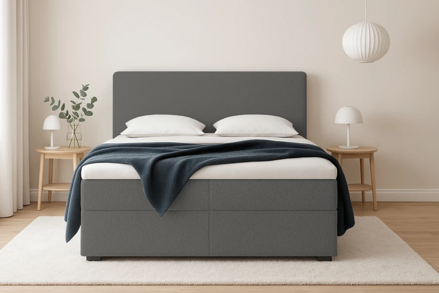 Modernes Boxspringbett in Grau mit gepolstertem Kopfteil und blauer Decke im Schlafzimmer.