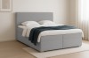 Cosy light grey Bouclé bed in the bedroom with light carpet and curtains.
