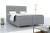 Graues Boxspringbett in modernem Schlafzimmer mit Pflanze und Designerlampe.