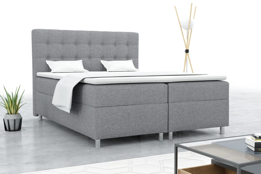 Graues Boxspringbett in modernem Schlafzimmer mit Pflanze und Designerlampe.