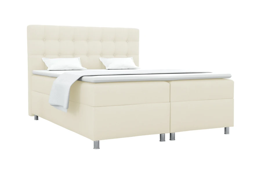 Beiges Boxspringbett mit gepolstertem Kopfteil und silbernen Füßen vor weißem Grund.