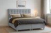 Modernes graues Boxspringbett mit gepolstertem Kopfteil in einem hellen Schlafzimmer.