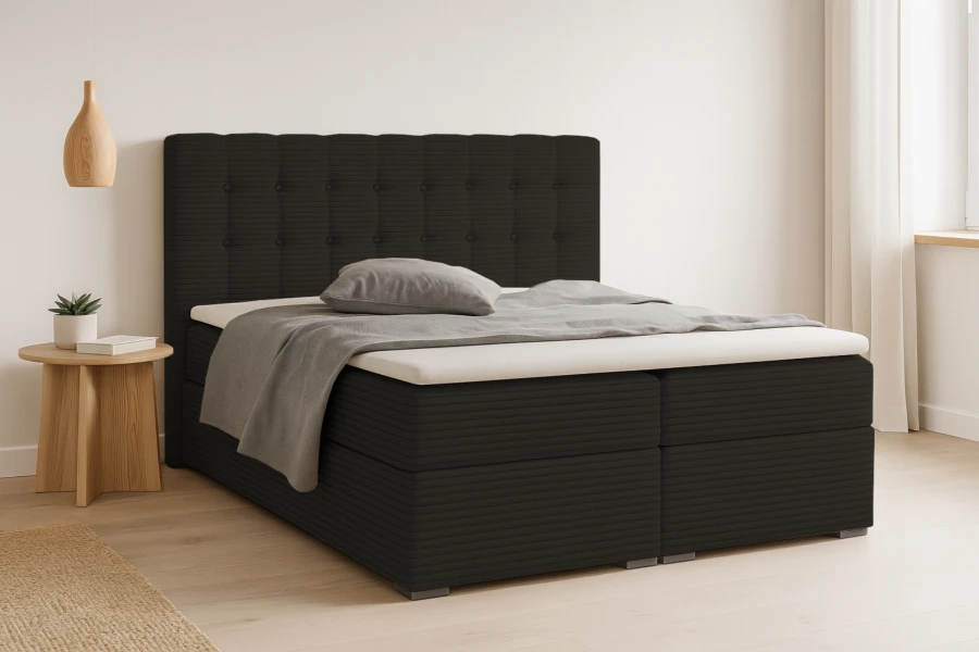 Modernes anthrazitfarbenes Boxspringbett mit gestepptem Kopfteil in einem hellen Schlafzimmer.